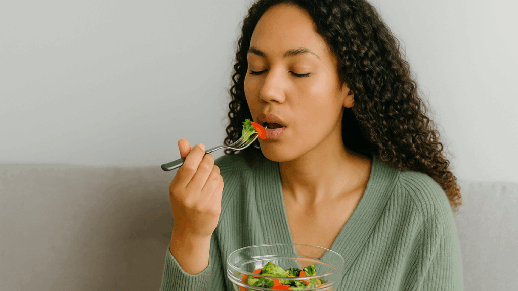 Mulher com expressão tranquila saboreando salada em ambiente calmo