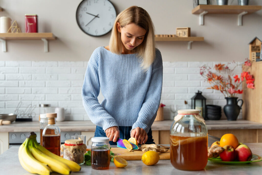 Mulher preparando chá emagrecedor com limão e gengibre na cozinha.