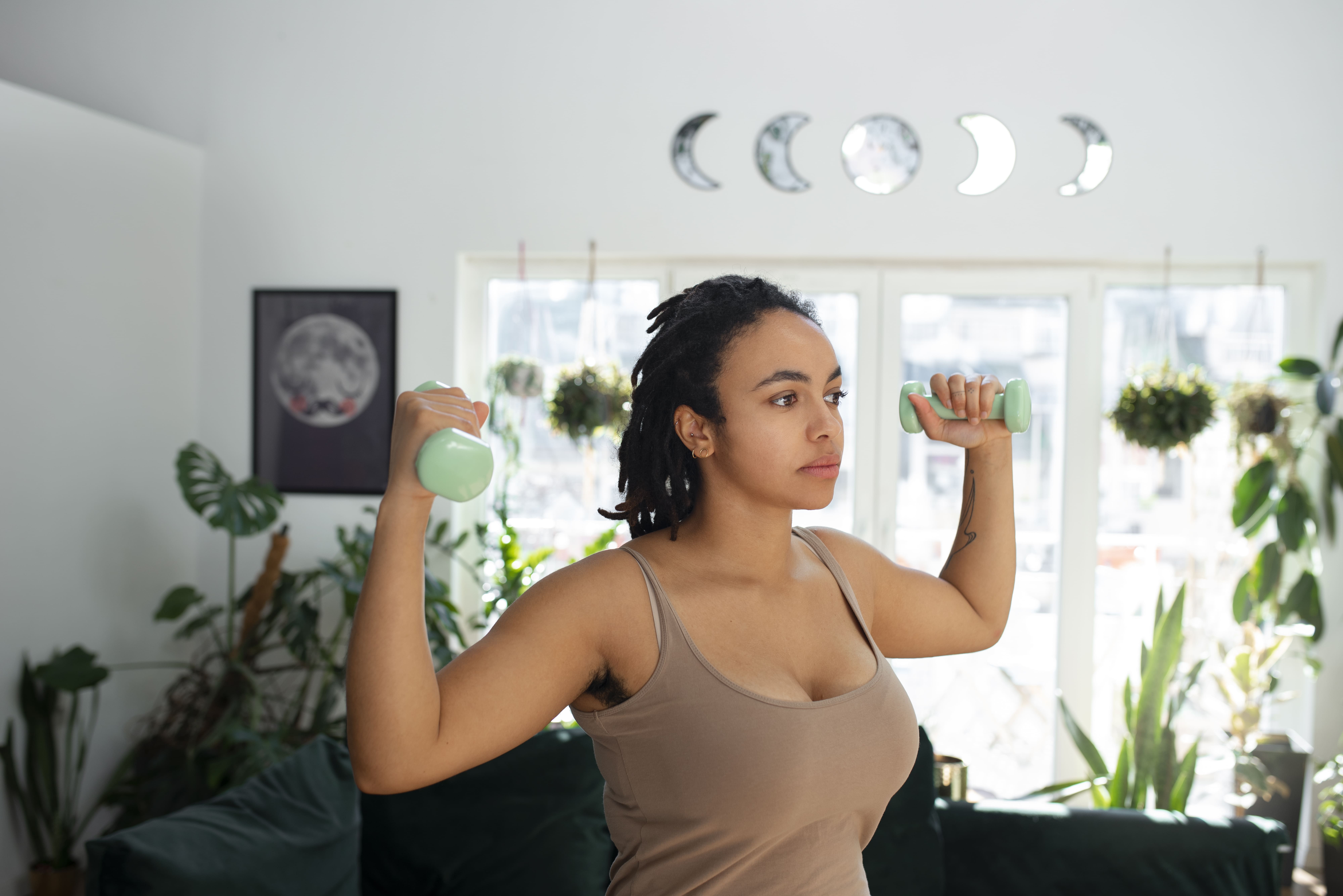 Mulher praticando exercícios físicos em casa com halteres, mostrando como o treino regular contribui para o emagrecimento sustentável.