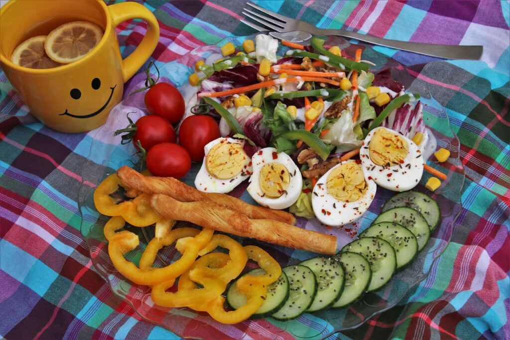 Prato saudável com ovos cozidos, legumes frescos e salada colorida, acompanhado de chá, ideal para uma dieta equilibrada e sustentável.