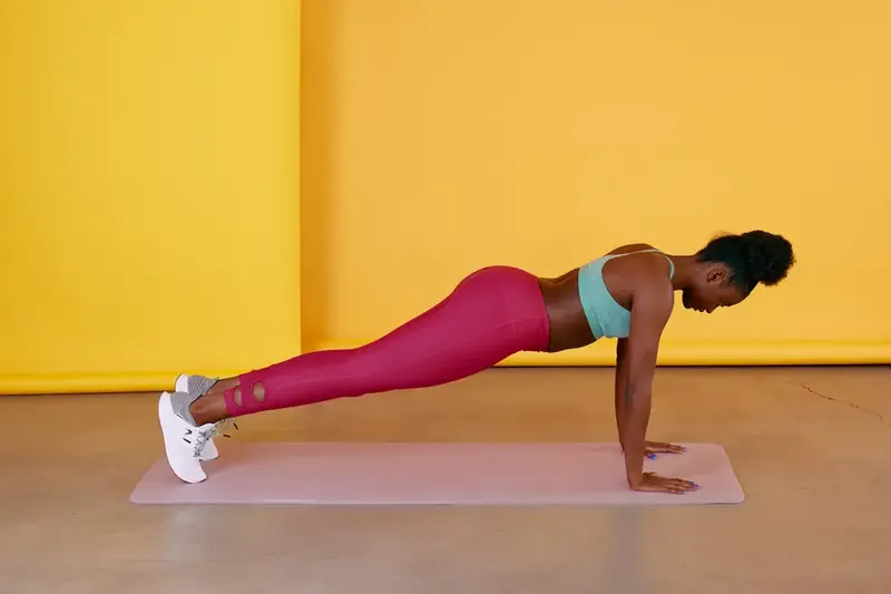 Mulher realizando exercício prancha no chão para fortalecer o corpo e ajudar no emagrecimento