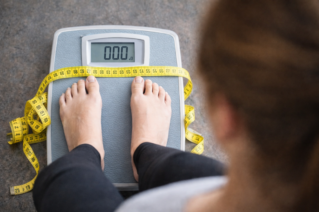 pessoa em pé na balança com fita métrica representando recuperação de peso após dieta