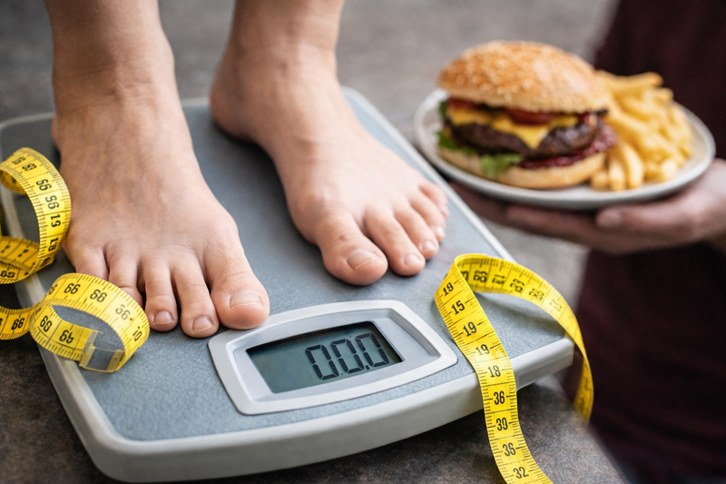 pessoa em pé na balança com fita métrica mostrando recuperação de peso após dieta