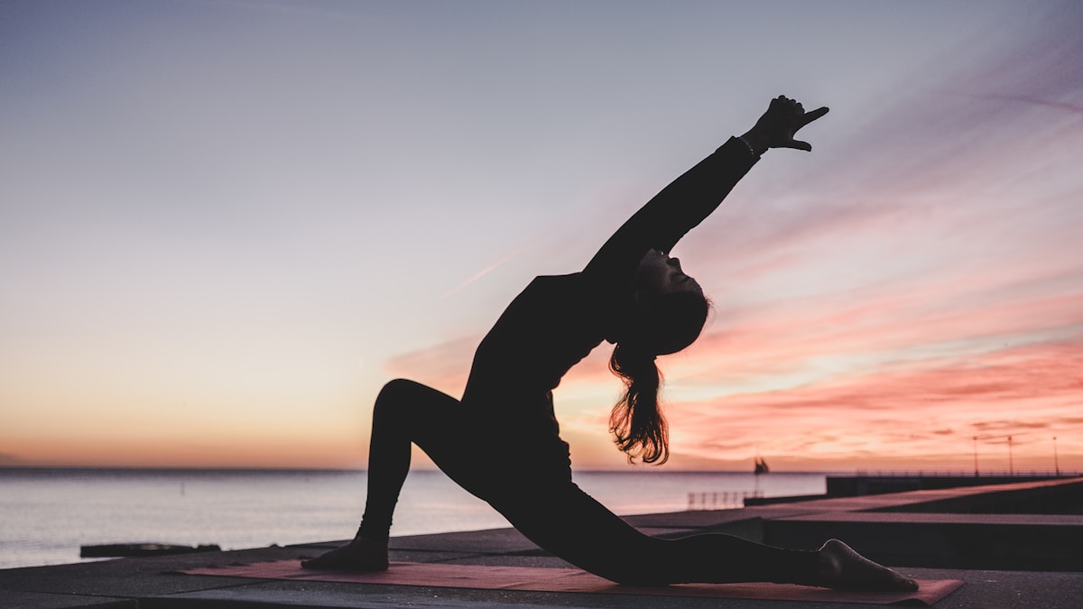 Mulher meditando pela manhã próximo à janela com luz solar Mulher praticando meditação matinal próximo à janela com luz natural, hábito para emagrecer