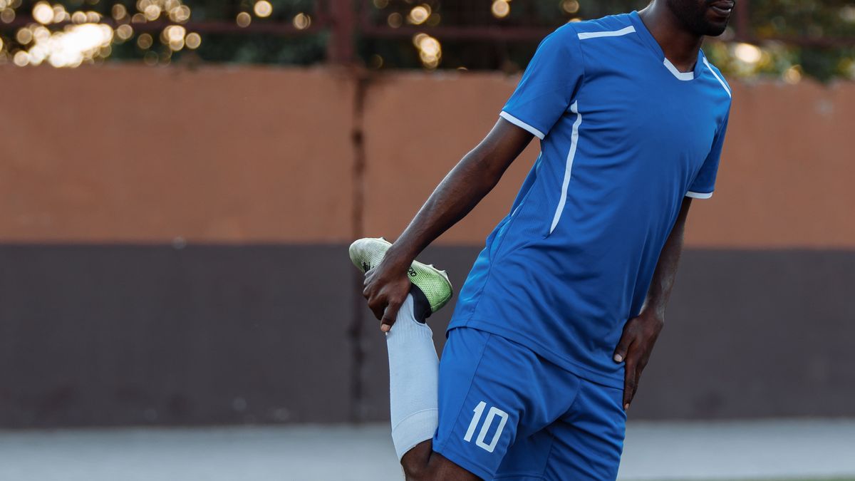 jogador de futebol fazendo aquecimento no campo para emagrecer jogando bola