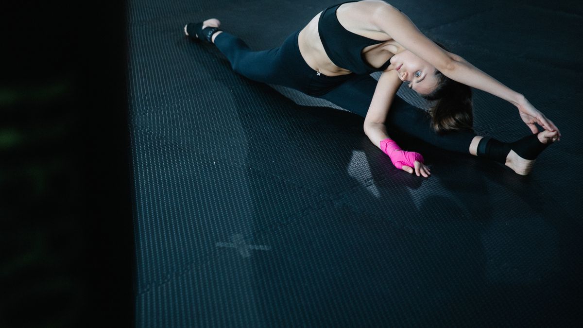 Mulher se alongando no tapete de yoga em casa