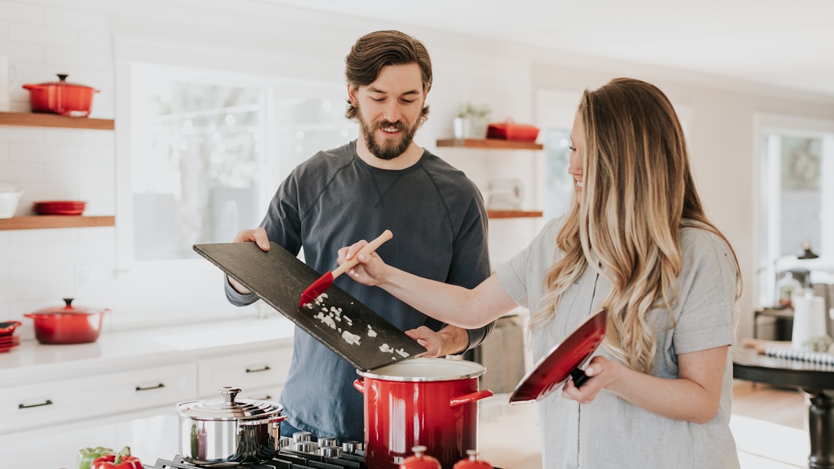 Homem preparando refeição saudável na cozinha — alimentação consciente para viver mais Homem adulto sorrindo enquanto prepara uma refeição saudável e colorida na cozinha de casa