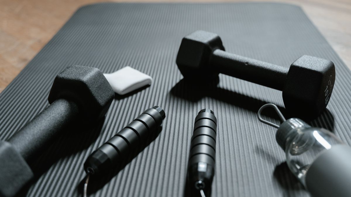 halteres corda de pular e garrafa de água em tapete de yoga para treino em casa