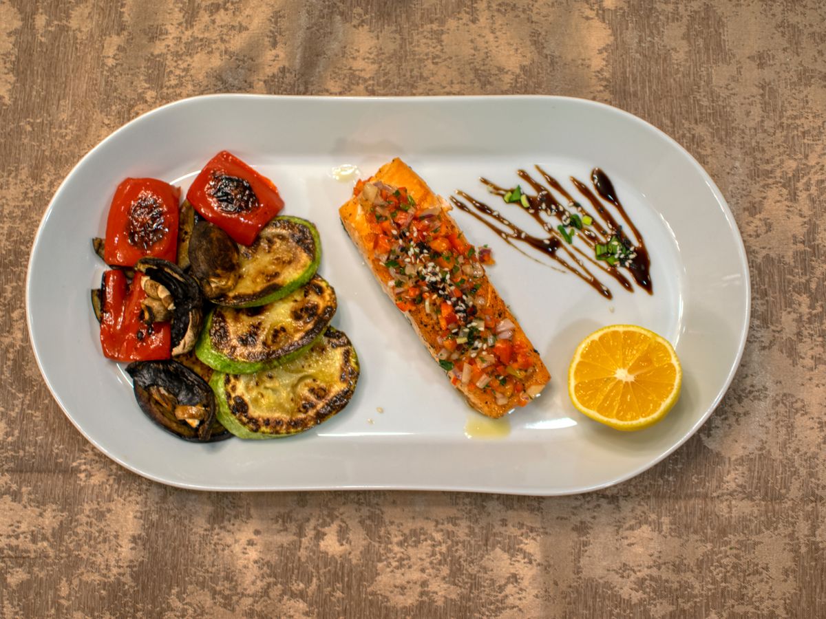 Salmao grelhado servido com vegetais e fatia de limao