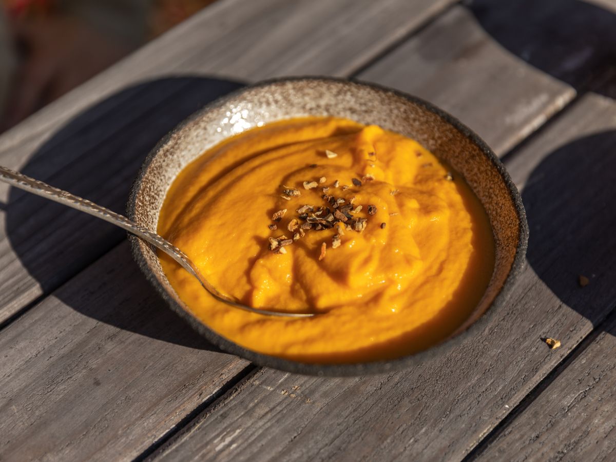 Sopa de abobora servida em tigela rustica, textura cremosa e reconfortante
