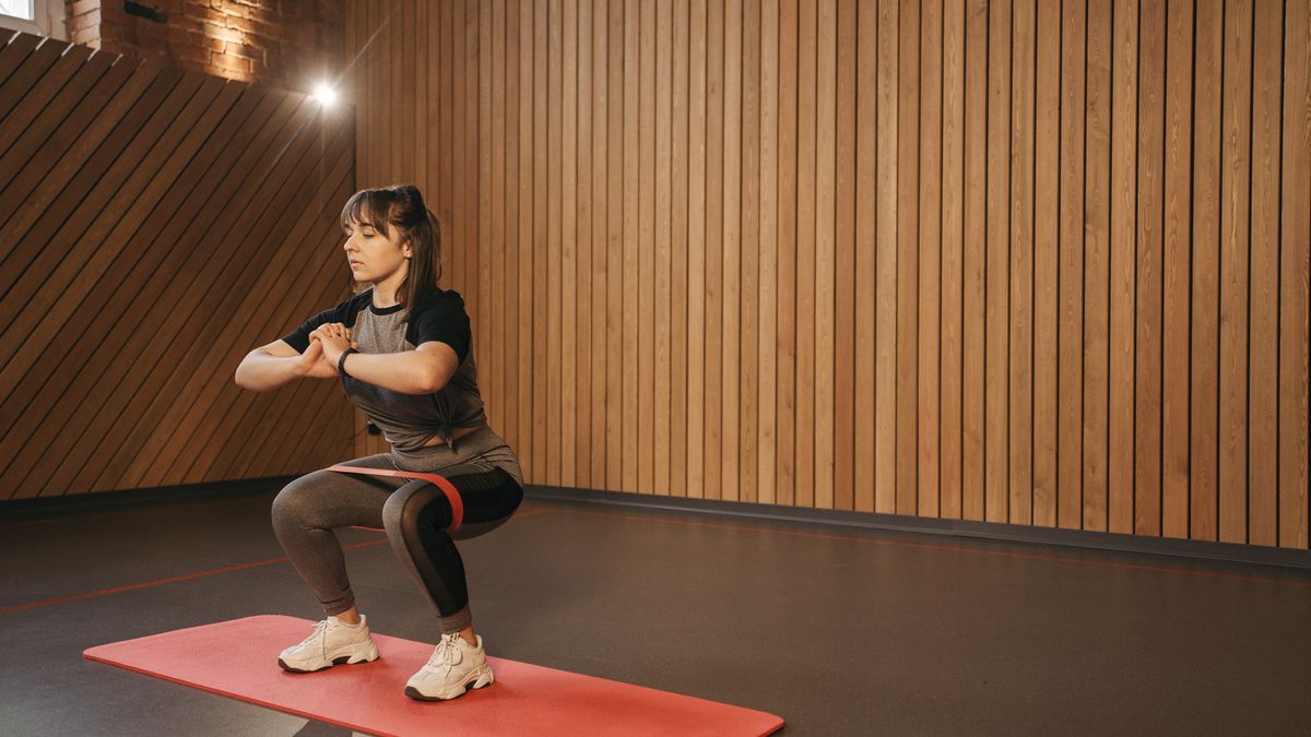 exercício com elástico no tapete para tonificar pernas e glúteos