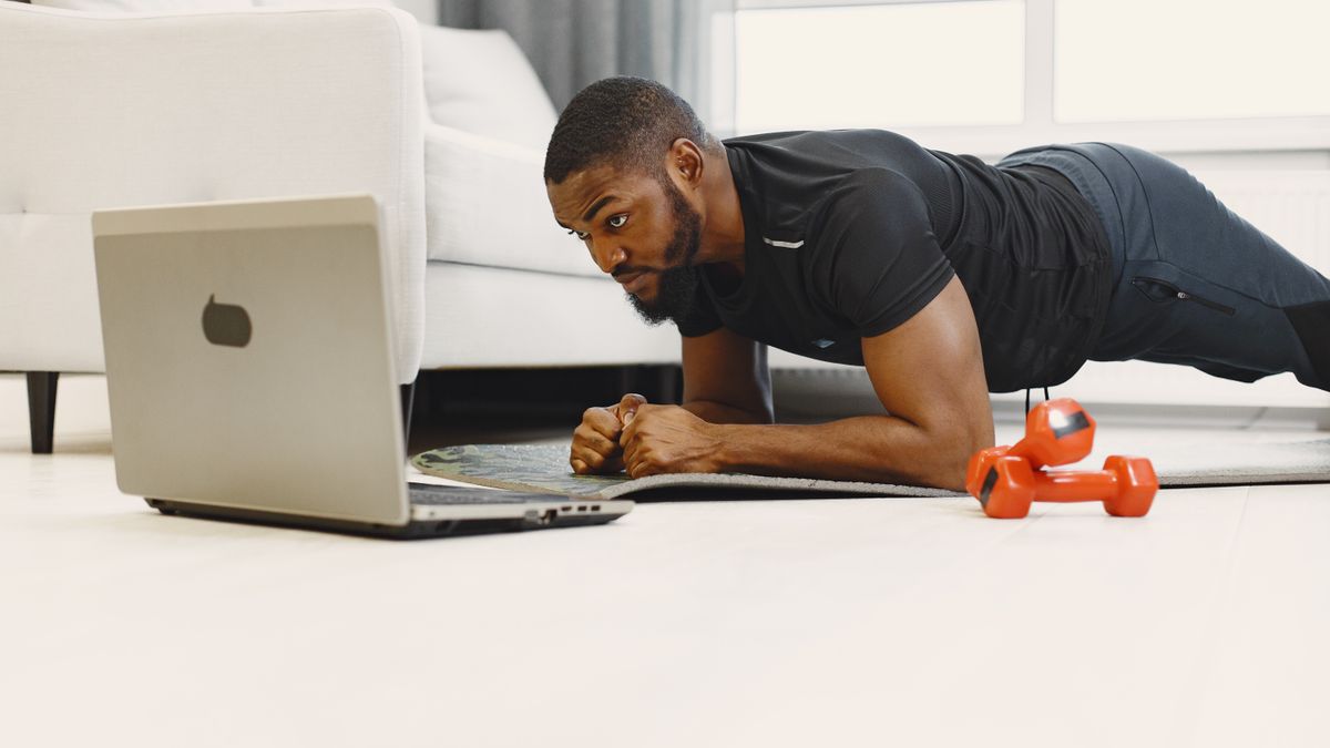 homem fazendo prancha em casa seguindo treino no laptop